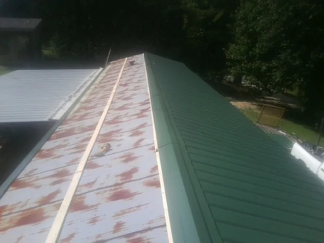 Old rusted panels beside newly installed green metal roofing — Wind Damage Roof Repair by Roofing Brothers in La Crosse